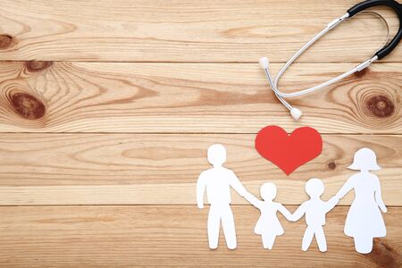 Family figures with red heart and stethoscope on brown wooden backgroundの写真素材