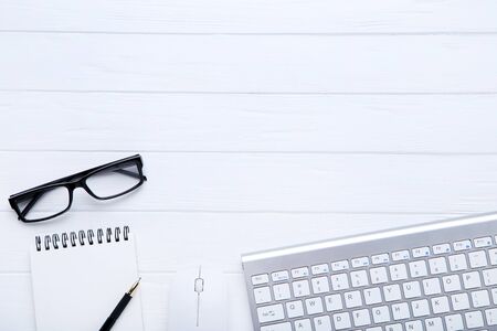 Computer keyboard with office supplies and glasses on white wooden tableの写真素材
