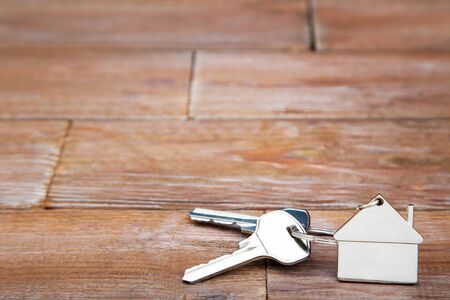 Silver keys with house symbol on brown wooden tableの写真素材