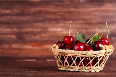 Sweet cherries in basket on brown wooden tableの写真素材