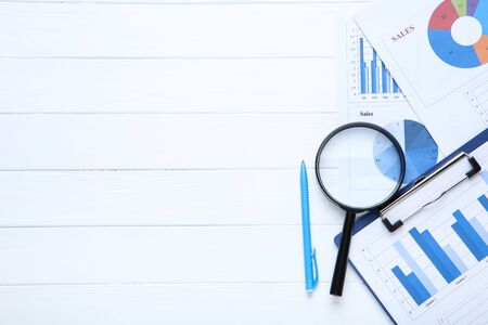 Financial papers with pen and magnifying glass on wooden tableの写真素材