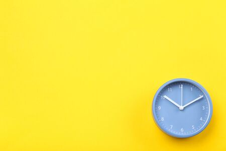 Blue round clock on yellow backgroundの写真素材