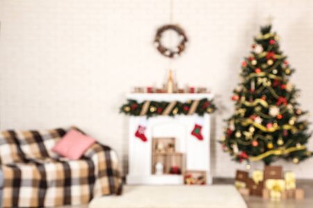 Blurred background of white decorated fireplace near sofa and christmas treeの写真素材
