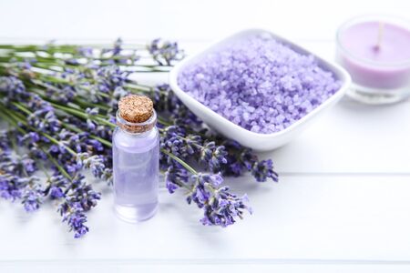 Lavender flowers with oil in bottle and salt in bowl on white wooden tableの写真素材