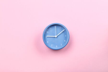 Blue round clock on pink backgroundの写真素材