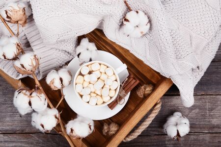 Cotton flowers with cup of cofffee and sweater on wooden tableの写真素材
