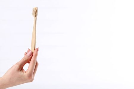 Bamboo toothbrush in female hand on white backgroundの写真素材