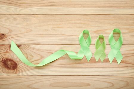 Green ribbon on brown wooden table. Medical conceptの写真素材