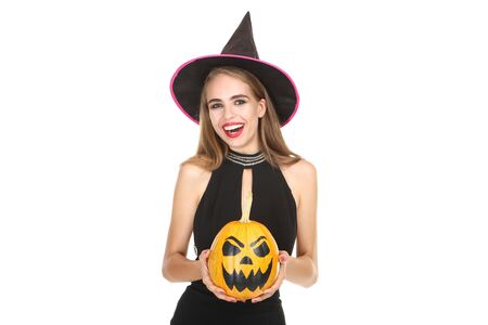 Beautiful woman in black costume holding halloween pumpkin on white backgroundの写真素材