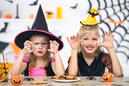 Young girls in halloween costumes sitting by the tableの写真素材