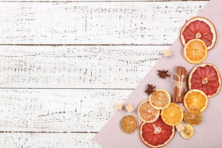 Dried citrus fruits with cinnamon, star anise and sugar cubes on white wooden tableの写真素材