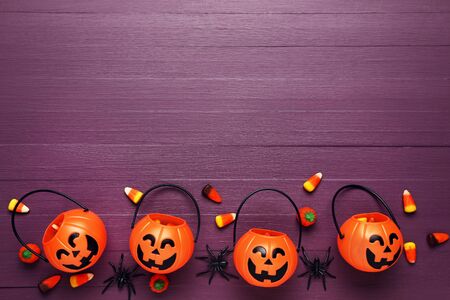 Halloween candies with pumpkin buckets and spiders on wooden table