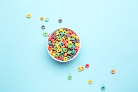 Colorful corn rings in bowl on blue background