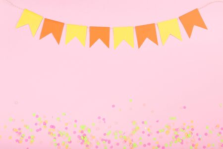 Colorful confetti and paper flags on pink background