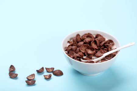 Chocolate corn flakes in bowl with milk and spoon on pink backgroundの写真素材