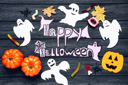 Text Happy Halloween with paper ghosts and pumpkins on wooden backgroundの写真素材