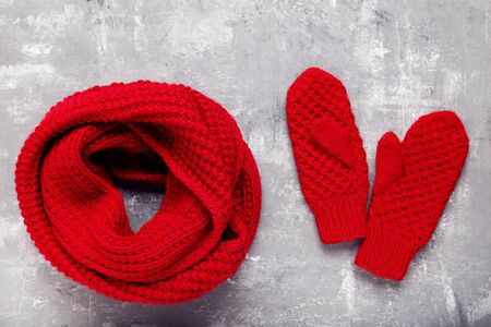 Knitted red scarf and pair of gloves on grey backgroundの写真素材