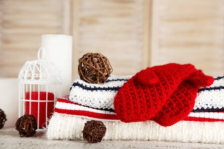 Folded knitted sweaters with pair of gloves and decoration balls on wooden tableの写真素材