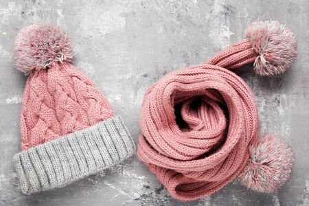 Knitted hat and scarf on grey background