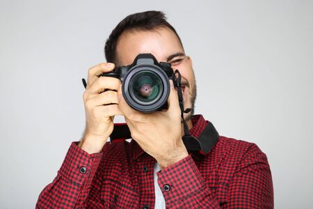 Young photographer with camera on grey backgroundの写真素材