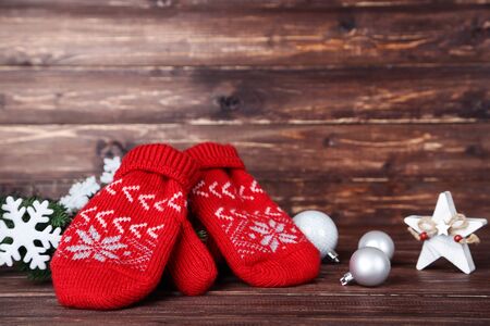 Knitted mittens with christmas ornaments on brown wooden backgroundの写真素材