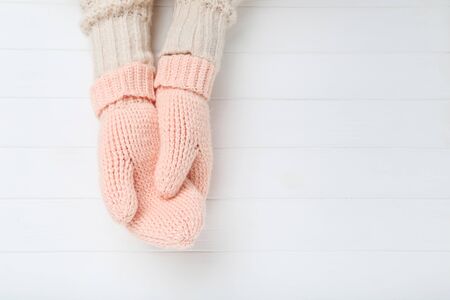 Hands in knitted mittens on white wooden tableの写真素材