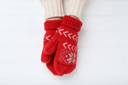 Hands in knitted mittens on white wooden tableの写真素材