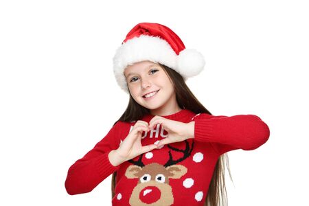 Little girl in christmas sweater and hat showing heart by hands isolated on whiteの写真素材