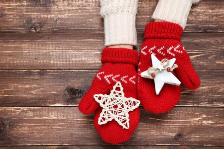 Hands in knitted mittens with two stars on brown wooden tableの写真素材