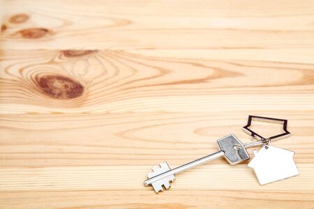 Silver key with house symbol on brown wooden table