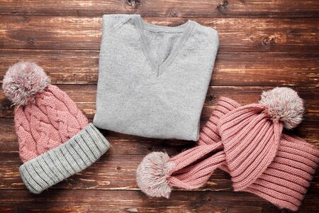 Knitted sweater with hat and scarf on brown wooden tableの写真素材