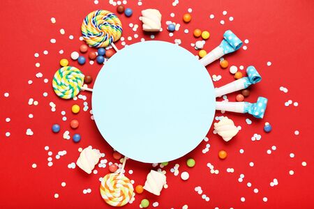 Colorful flat lay composition with various party items and candies on red backgroundの写真素材
