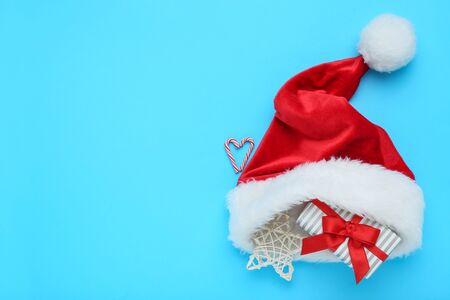 Red santa hat with gift box, star and candies on blue backgroundの写真素材