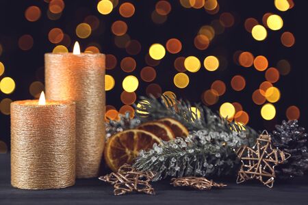Christmas candles with stars, dry oranges and fir tree branches on blurred backgroundの写真素材