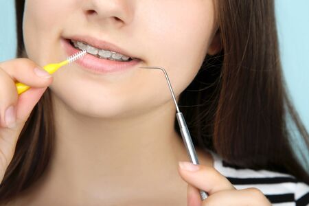 Young girl with dental braces holding toothbrush and dentist tool