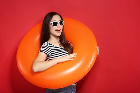 Young girl with inflatable ring on red backgroundの写真素材