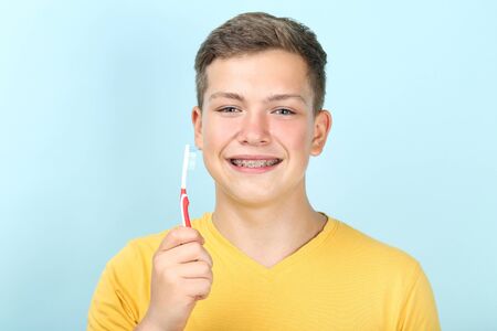 Young man with toothbrush on blue backgroundの写真素材