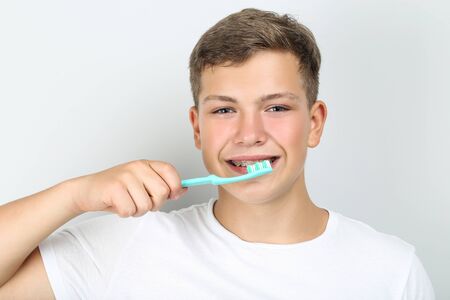 Young man with toothbrush on grey backgroundの写真素材