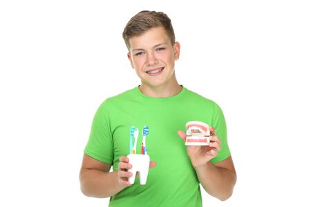 Young man with toothbrushes and teeth model on white backgroundの写真素材