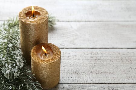 Christmas candles with fir tree branches on white wooden tableの写真素材