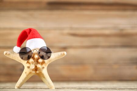 Red santa hat with starfish and sunglasses on wooden backgroundの写真素材