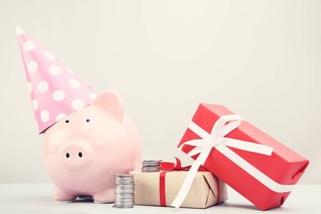 Pink piggy bank with gift boxes and coins on grey backgroundの写真素材