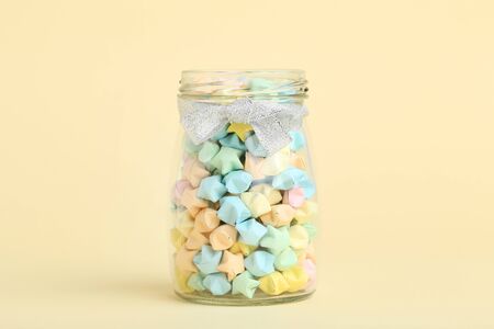 Colorful paper stars in glass jar on beige backgroundの写真素材