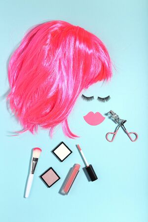 Pink wig with makeup cosmetics on blue background. Minimalism conceptの写真素材