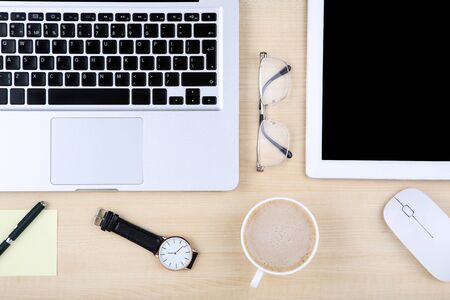 Tablet, laptop computer with glasses, mouse and cup of coffee on wooden tableの写真素材