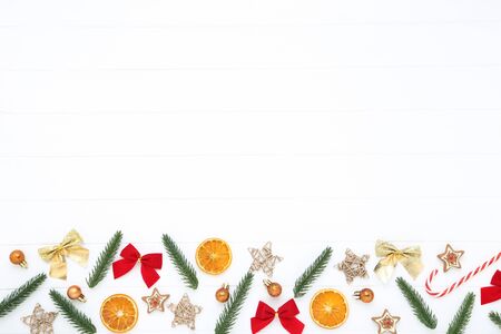 Christmas tree branches with toys, candies and orange fruits on white wooden tableの写真素材