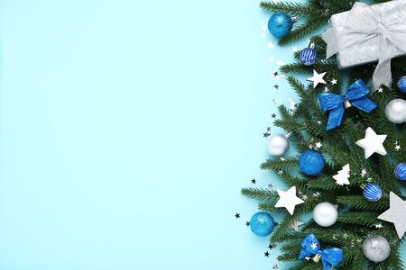 Christmas tree branches with toys and gift box on blue backgroundの写真素材