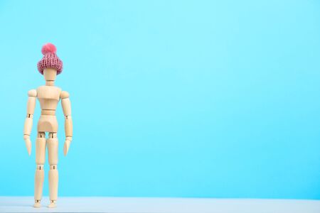 Wooden figure in pink hat on blue backgroundの写真素材