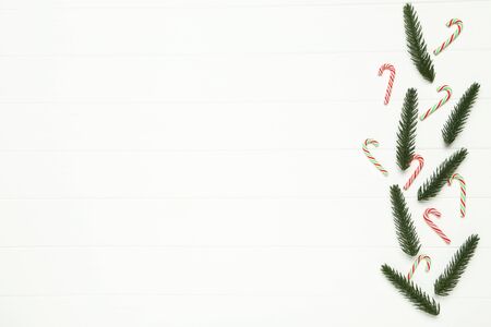Flat lay christmas composition. Fir tree branches and candies on white wooden tableの写真素材