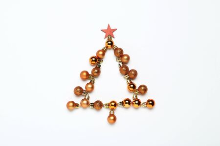Flat lay christmas composition. Golden baubles in shape of fir tree on white backgroundの写真素材